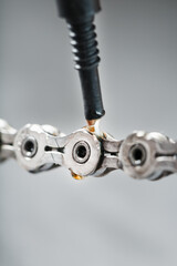 Greasing a bicycle chain with a drop of golden oil close-up on a gray background