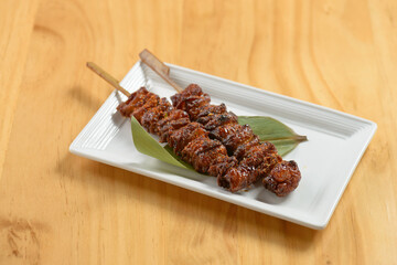 Japanese BBQ Kawa kebab sticks in a white tray on wooden background top view