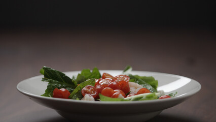 making salad cherry tomatoes fall over romaine leaves in white bowl