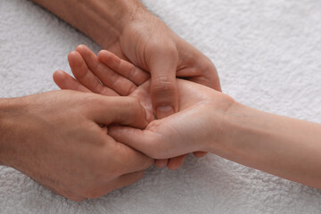 Woman receiving hand massage on soft towel, closeup