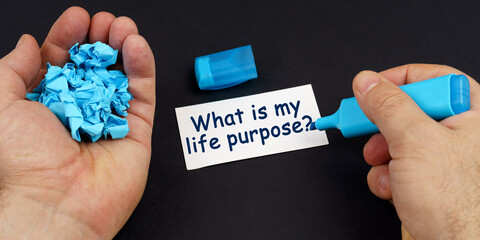 In the hands of crumpled paper, a marker, next to a business card with the inscription - What is my life purpose