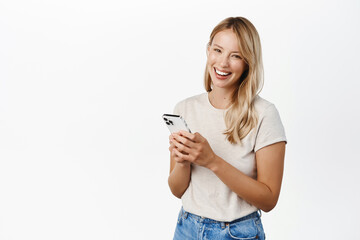 Cellular technology, mobile apps concept. Smiling beautiful woman using smartphone, looking at her...