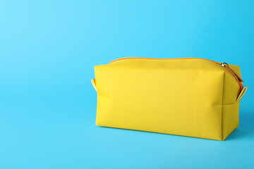 Yellow cosmetic bag on light blue background. Space for text