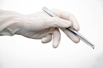 Forceps in doctor hand with disposable glove on white background.