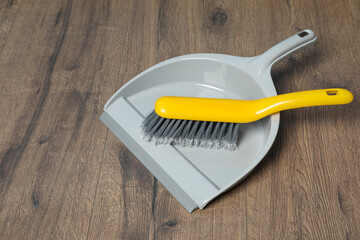 Plastic whisk broom with dustpan on wooden floor