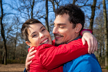 Fototapeta premium Young couple is hugging happy in the woods. Beautiful couple have fun while hiking in the woods in Italy.