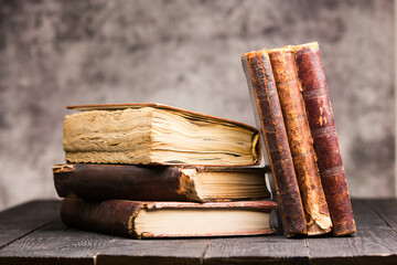 Vintage leather books stack on old rustic wooden surface