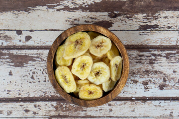 Dried banana chips in a wooden plate.