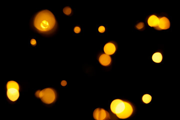 Gold bokeh on dark background. Defocused golden lights. New Year, Christmas background, abstract texture.