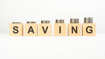 saving text written on wooden block with stacked coins on white background