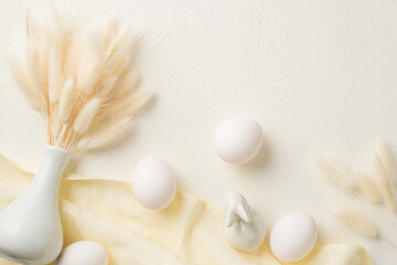Top view photo of easter decorations white vase with lagurus flowers ceramic bunny easter eggs and cloth on isolated white background with copyspace