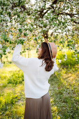 Obraz premium Young woman enjoying scent in blooming spring garden. The concept of relax, travel, freedom and spring vacation. Fashion style