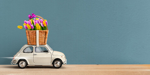 White Retro toy car carrying flowers in a wicker basket