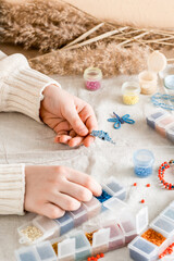 The girl's hands are weaving a dolphin on a table with items for beading. Development of creative skills and fine motor skills for children. Top and vertical view.
