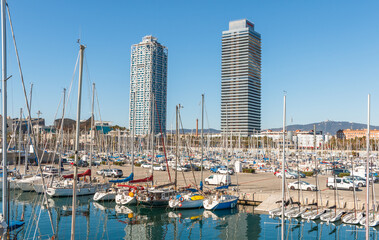 Fototapeta na wymiar Barcelona towers captured during a sunny day between boats. Barcelona olympic port.