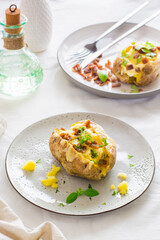Twice-baked potatoes in their skins with cheese and bacon crumbs on plates on a wooden table. Flexitarian Diet. Vertical vew