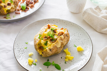 Appetizing twice-baked potatoes in their skins with cheese and bacon crumbs on plates on a wooden table. Flexitarian Diet. Close-up