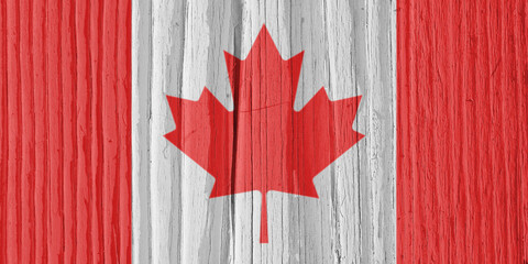 Canadian flag on a dry wooden surface. Natural background, wallpaper or backdrop made of old wood. The official symbol of Canada. Solar lighting with hard shadows. Aspect ratio 2:1