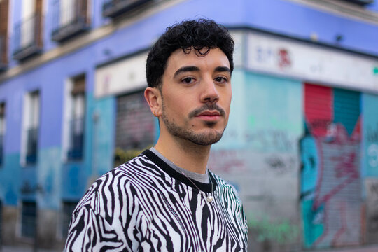 Young hispanic man with serious expression standing at the city