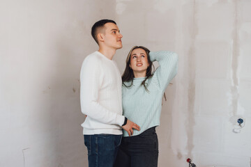 Couple in unfinished building. Woman and men thinking about apartment renovation. Young couple in new property.Family buy new flat.