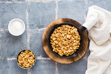 Fresh roasted peanuts in a frying pan, salt and oil on the table. Plant source of protein. Vegetarian food. Top view