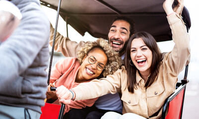 Multiracial students cheering on rickshaw at travel location - Life style concept with guys and girls having fun together - College mates riding around the city after school vacations - Bright filter