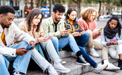 Bored friends group using mobile smart phone sitting at university college yard - Young people...