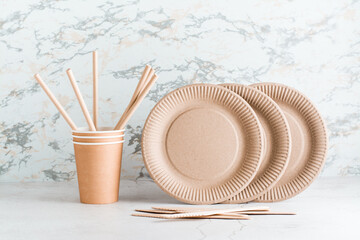 Eco friendly disposable cardboard tableware. Plates, cups and pipes and wooden knives on the table.