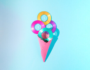 Ice cream cone filled with a mini cd against a blue background. Vintage minimal summer concept idea