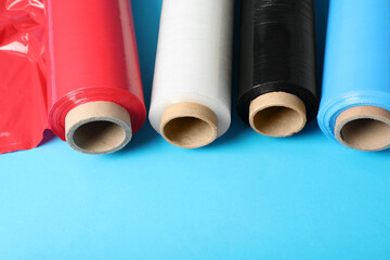 Rolls of different plastic stretch wrap on light blue background. Space for text