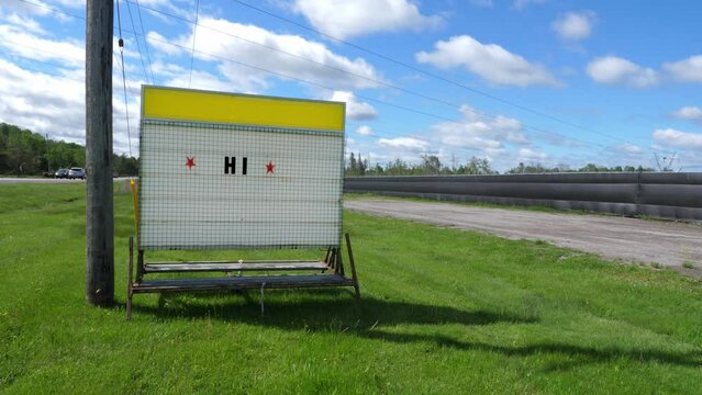 Roadside billboard sign saying HI. Summer day in Ontario, Canada.