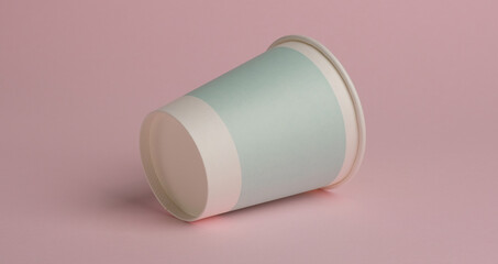 one paper cup lies on a pink background