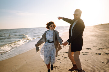 Stylish couple walking and hugging by the sea. Springtime. Relaxation, youth, love, lifestyle solitude with nature.