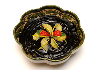 black sapote dessert, black sapote candy with orange juice served on a ceramic plate garnished with...