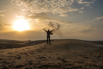 Woman throwing sand on the dunes of a beach at sunset. Freedom