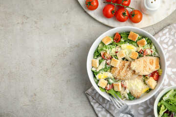 Delicious fresh Caesar salad in bowl on light grey table, flat lay. Space for text