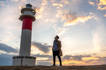 Man next to a lighthouse at sunset.