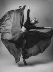 Woman Dancer jumping with Silk Fabric dress Fluttering Weaving Cloth on Gray Background