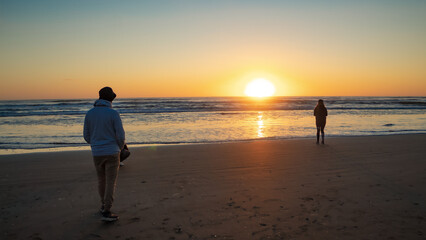 wo young people watch the sunrise over the sea. New day on the Argentine coast.