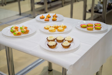 Assortment of delicious fresh shortcrust tart cakes with cream on white plate for sale at restaurant, cafe, bakery. Dessert, culinary, sweet food and confectionery concept