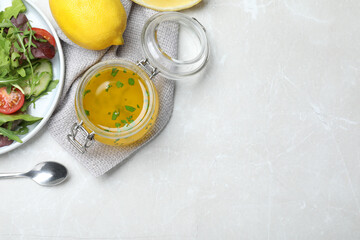Jar of lemon dressing near salad on light table, flat lay with space for text
