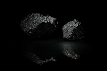 Black rocks on a dark background. A wallpaper. Minerals in reflection. A desktop image.