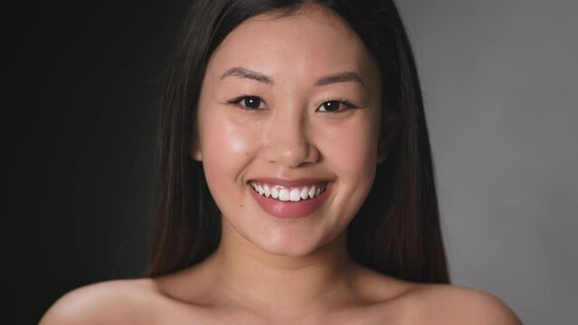 Asian beauty. Close up portrait of young gorgeous well-groomed woman smiling to camera, slow motion