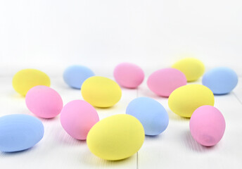 Many multi-colored Easter eggs are scattered on a light background
