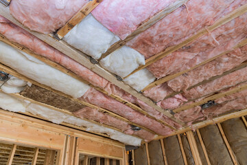 Mineral glass wool in a wooden frame on a inclined wall near the wooden ceiling a private house