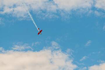 Small retro airplane, light aircraft flying in blue cloudy sky and doing stunts at Air Show. Performance, extreme, aerobatic and sport concept