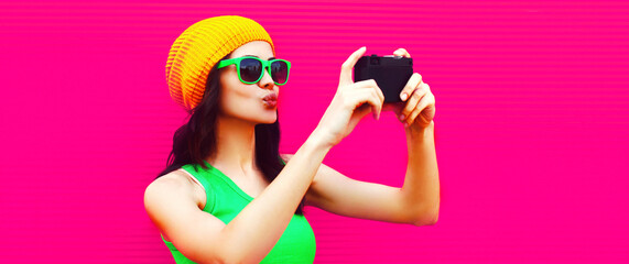Summer colorful portrait of happy modern young woman taking selfie by camera on pink background