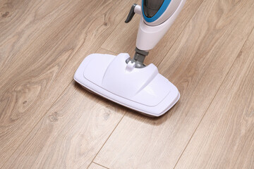 A man washes laminate flooring with a steam mop. Killing germs, clean floor, decontamination.