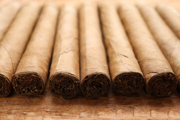 Many cigars on wooden table, closeup. Tobacco smoking