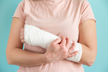Woman with broken arm, fractured wrist. Hand in a plaster bandage, gypsum bandage.